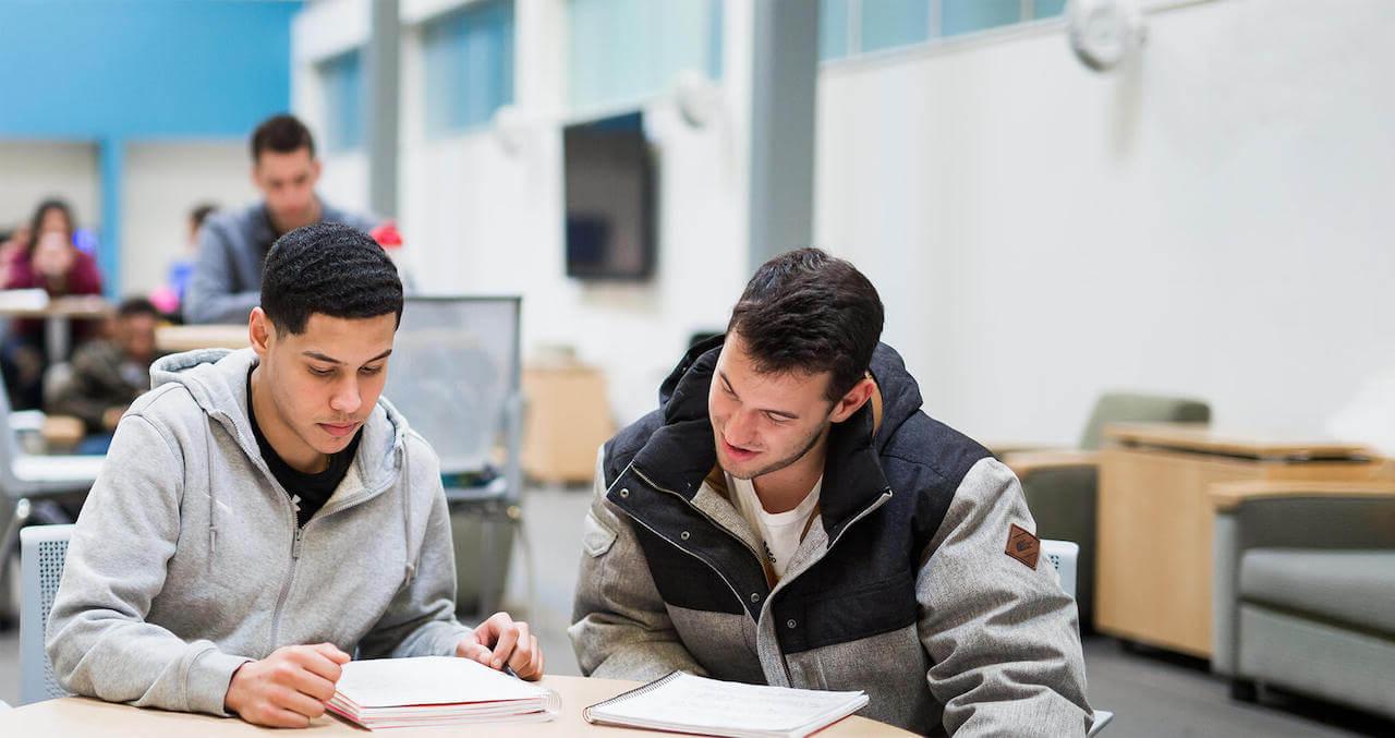 Two Student sitting at a table with note books open